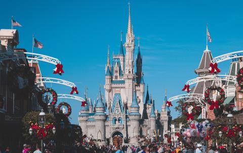 View of a blue, pink, and cream-colored castle, Disney's Cinderella castle, in Disney world with blue sky in the background